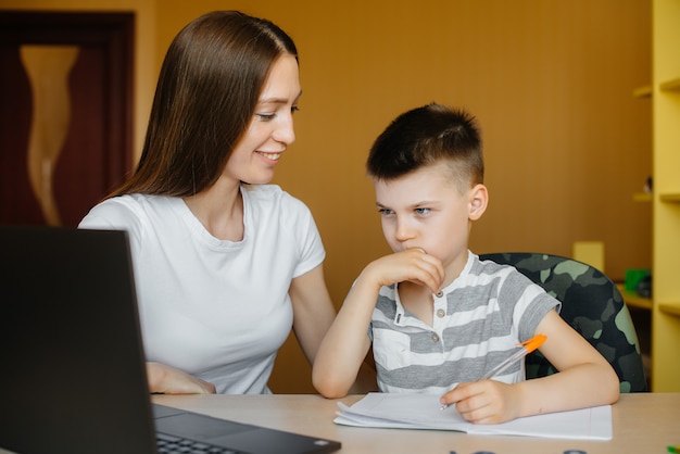 Una madre y su hijo participan en el aprendizaje a distancia en casa frente a la computadora. Quédate en casa, entrenando.