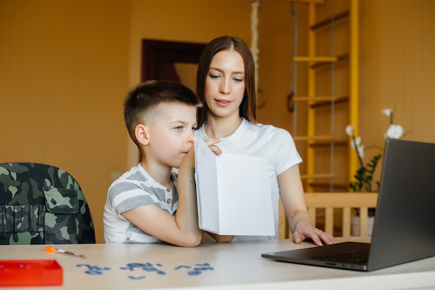 Una madre y su hijo participan en el aprendizaje a distancia en casa frente a la computadora. Quédate en casa, entrenando.