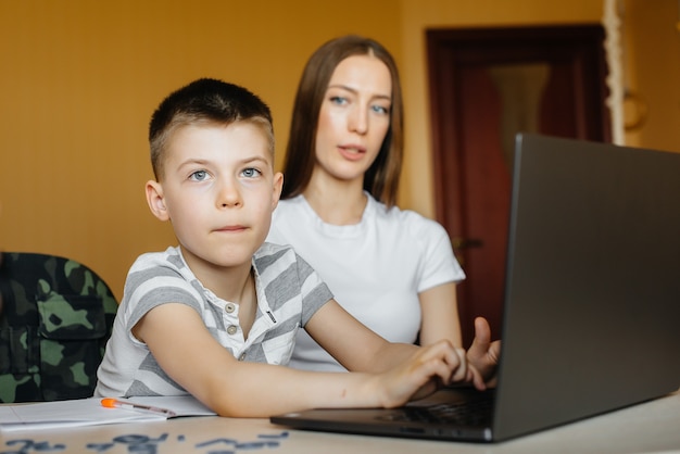 Una madre y su hijo participan en el aprendizaje a distancia en casa frente a la computadora.