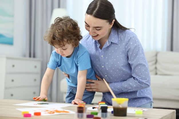 Madre y su hijo pequeño pintando con palmeras en casa