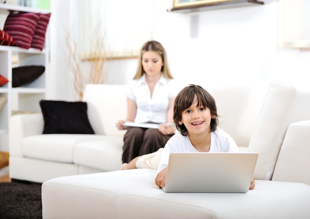 Madre y su hijo tener tiempo de Dios juntos usando la computadora portátil en casa en el sofá