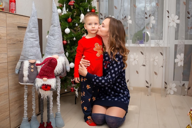 Una madre y su hijo tienen un lindo pijama de Año Nuevo que se pusieron cerca del árbol de Navidad