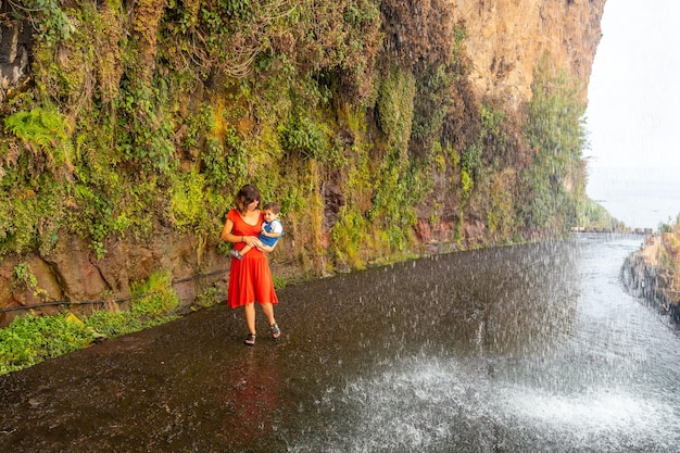 Una madre con su hijo con un vestido rojo en Anjos Waterfall Madeira