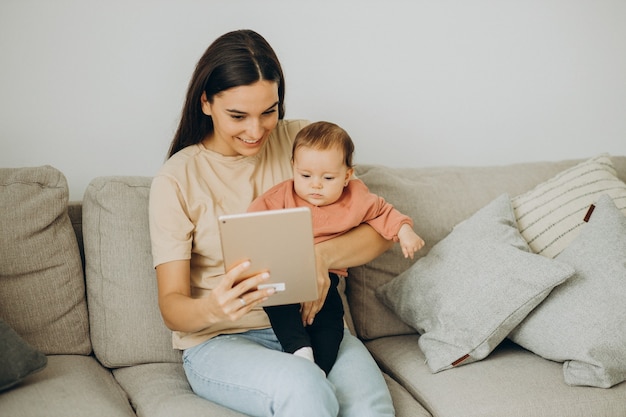 Madre con su niña bbay usando tableta en casa