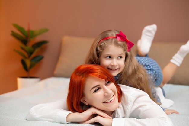 Madre y su niña hija en la cama en el dormitorio.