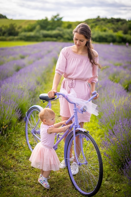 Madre con su pequeña hija en bicicleta púrpura sobre fondo lavanda República Checa