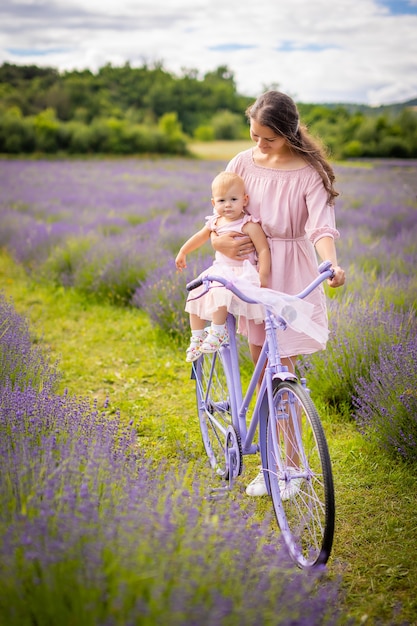 Madre con su pequeña hija en bicicleta púrpura sobre fondo lavanda República Checa