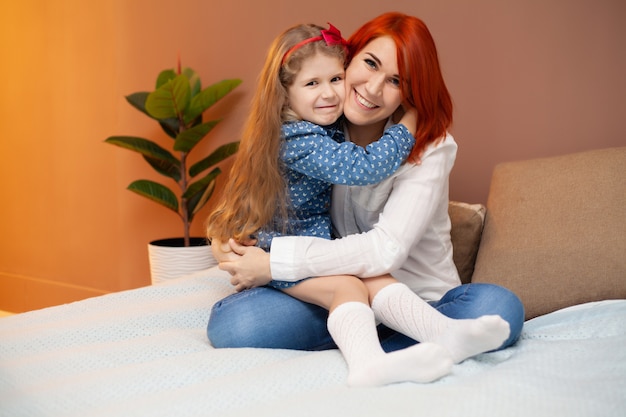 Madre y su pequeña hija en la cama en el dormitorio