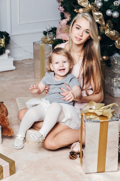 Madre con su pequeña hija cerca del árbol de Navidad en casa