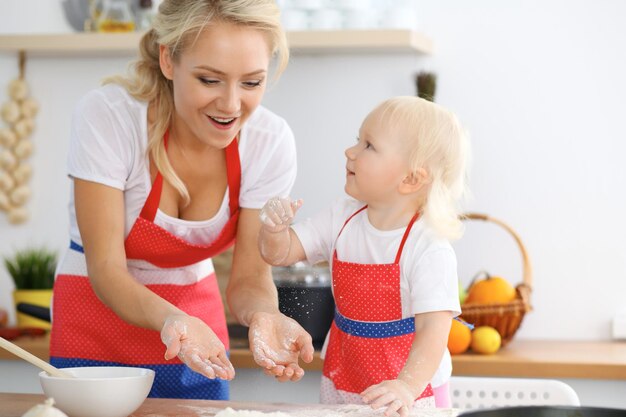 La madre y su pequeña hija cocinan pastel o galletas navideñas para el Día de la Madre Concepto de familia feliz en la cocina