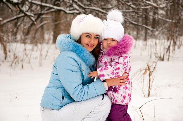 Madre y su pequeña hija disfrutando hermoso día de invierno al aire libre.