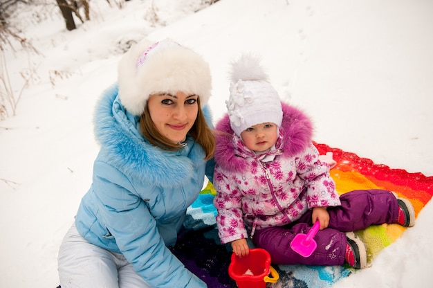 Madre y su pequeña hija disfrutando hermoso día de invierno al aire libre.