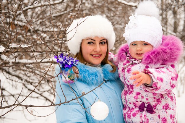 Madre y su pequeña hija disfrutando hermoso día de invierno al aire libre.