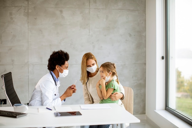 Madre con su pequeña hija en el examen del pediatra por doctora afroamericana