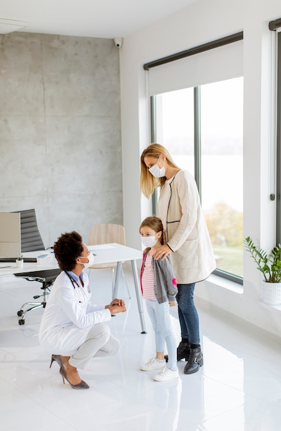 Madre con su pequeña hija en el examen del pediatra por doctora afroamericana