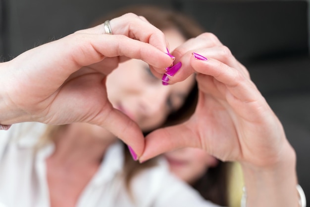 Madre y su pequeña hija mostrando forma de corazón con los dedos