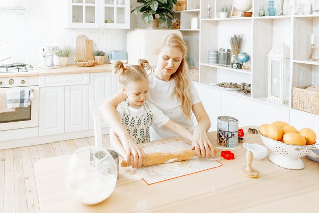 Una madre y su pequeña hija preparan masa para hornear juntas en la cocina de su casa.