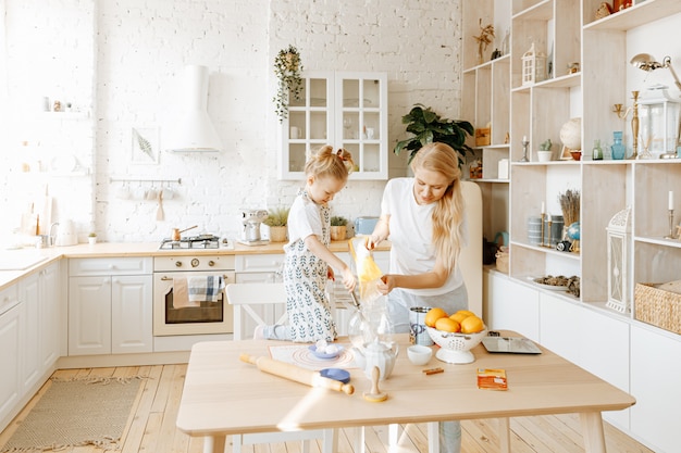 Una madre y su pequeña hija preparan masa para hornear juntas en la cocina de su casa.