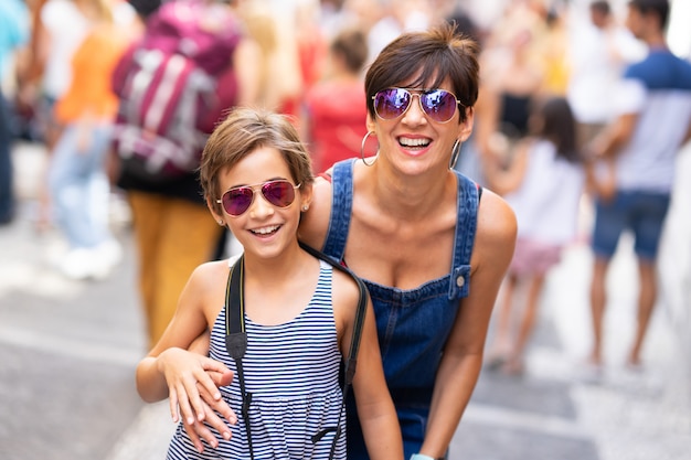 Madre y su pequeña hija viajando juntas en el fondo urbano.