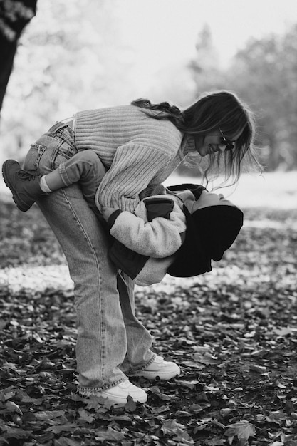 Madre con su pequeño hijo caminando en el parque otoñal