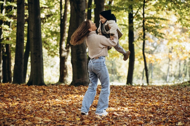 Madre con su pequeño hijo caminando en el parque otoñal