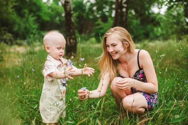 Una madre y su pequeño hijo recogen flores en un prado en verano