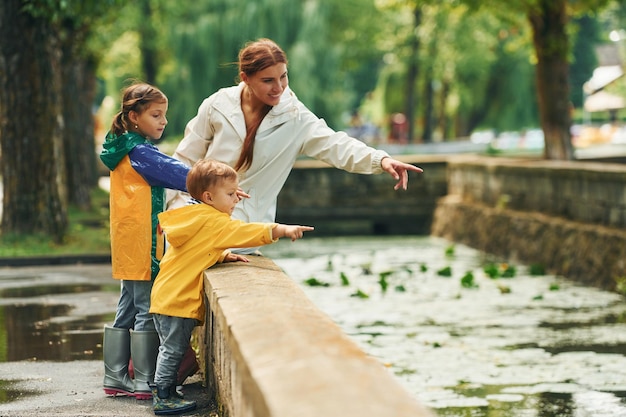 La madre con su pequeño hijo y su hija dan un paseo al aire libre en el parque después de la lluvia