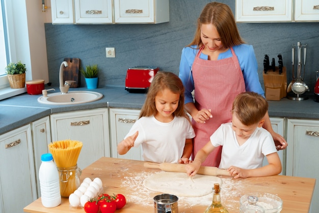 Madre y sus hijos cocinando masa en la cocina