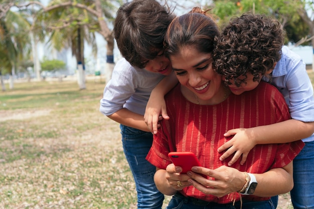 Madre con sus hijos mirando su teléfono celular