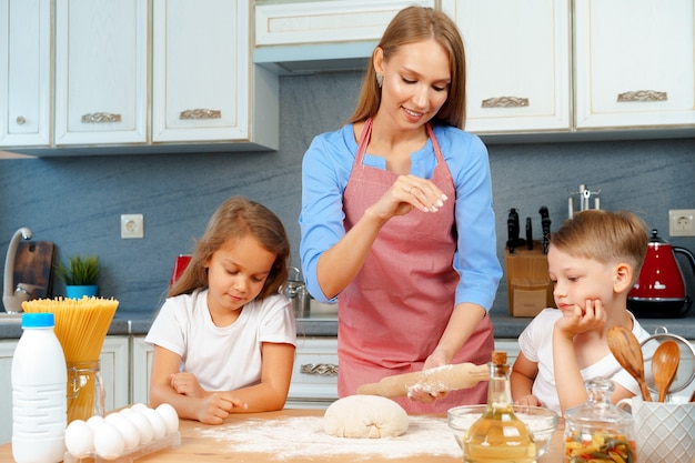 Madre y sus hijos pequeños, niño y niña, ayudándola a preparar la masa