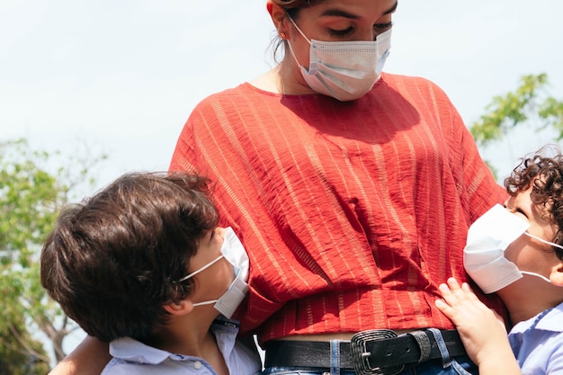 Madre con sus hijos vistiendo chicle protector al aire libre