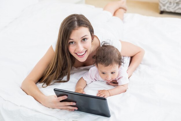 Madre con tablet PC con bebé en casa