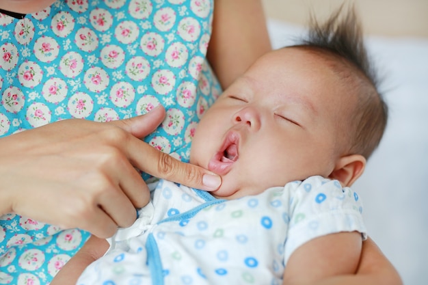 Madre tocando para abrir la boca del bebé