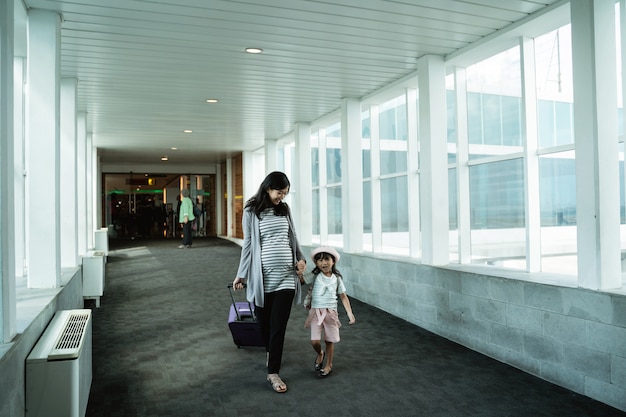 Madre toma las manos de una niña para abordar un avión