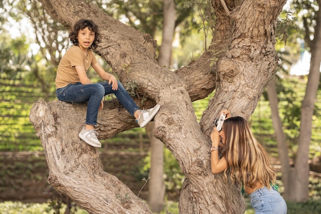 Madre tomando una foto de su hijo trepando a un árbol