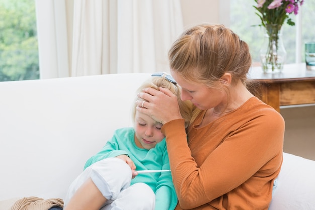 Madre tomando la temperatura de la hija enferma