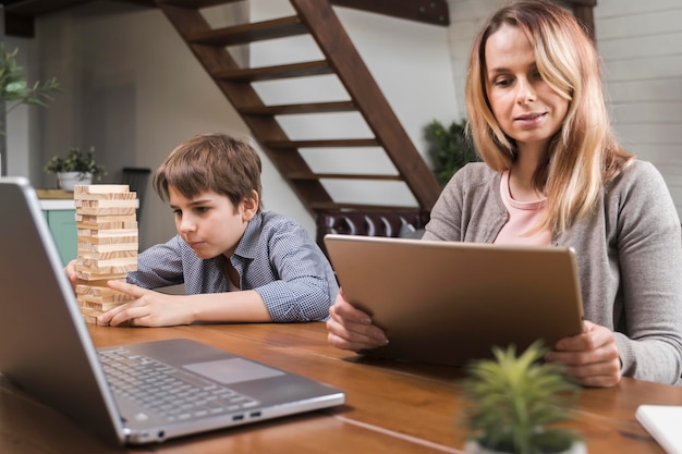 Foto madre trabajando desde casa mientras el hijo está jugando