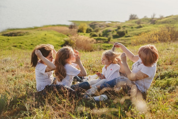 Una madre con tres hijas se sienta en la hierba en la playa en verano