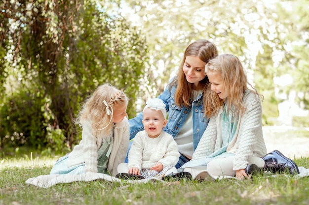 madre con tres hijas se sienta en un picnic en el verano y los mira con amor