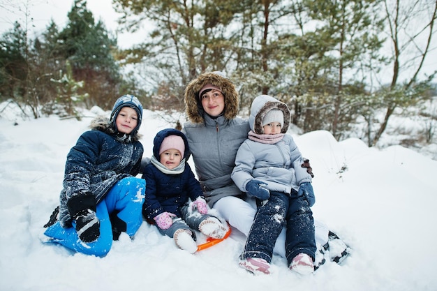 Madre con tres hijos en la naturaleza de invierno. Al aire libre en la nieve.