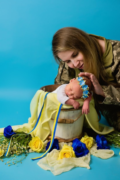 Una madre ucraniana en uniforme militar con un bebé en los colores de una bandera azul amarilla durante el