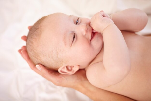 Las madres tienen el futuro en sus manos Pequeño bebé feliz acostado en las manos de su madre