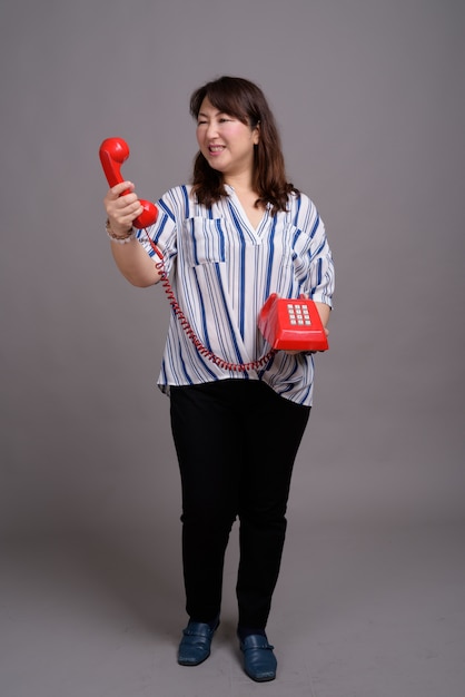 madura linda empresária asiática segurando o telefone