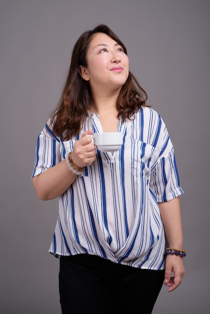madura linda empresária asiática segurando uma xícara de café