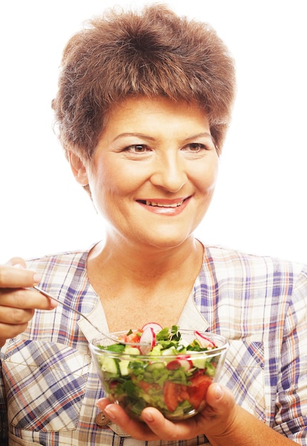 Madura mulher sorridente comendo salada