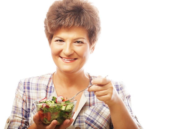 Madura mulher sorridente comendo salada