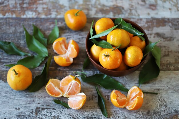 Maduras jugosas mandarinas en un tazón. Hojas de mandarina. Mandarinas frescas y fragantes. Cosecha de mandarinas.