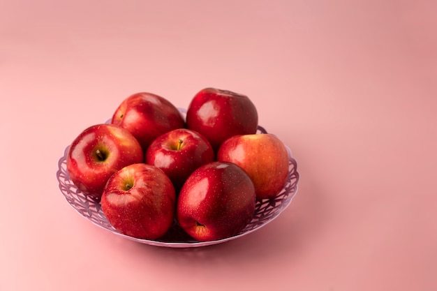 Maduras maçãs vermelhas vermelhas deliciosas, close-up em uma cesta em um rosa