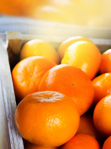 Maduras saborosas tangerinas com folhas em caixa de madeira, isoladas no branco