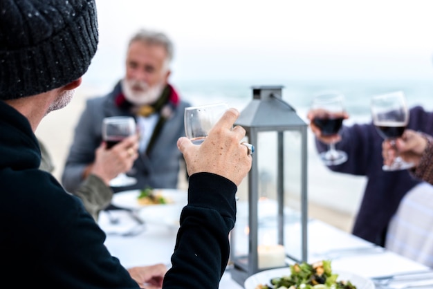 Maduros amigos bebendo vinho na praia